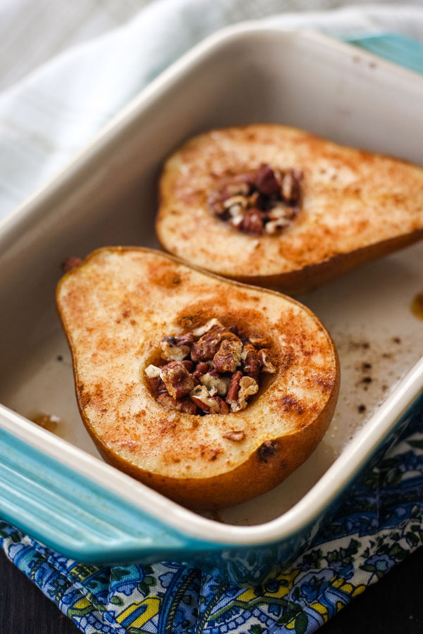 Small blue baking dish filled with two baked pear halves.