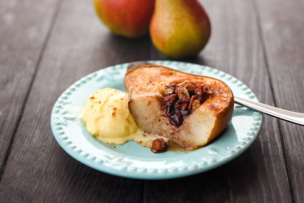 Half of a juicy baked pear with a scoop of vanilla ice cream.