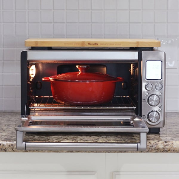 A red dutch oven inside of a countertop oven.