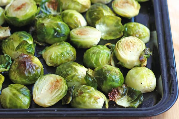 Roasted Brussels sprouts on a dark roasting pan.