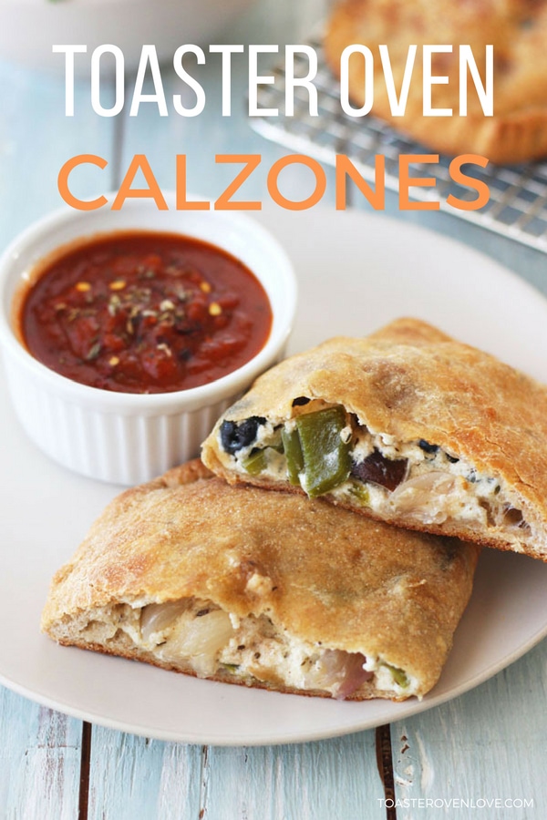 Baked calzone on a plate with a cup of marinara sauce