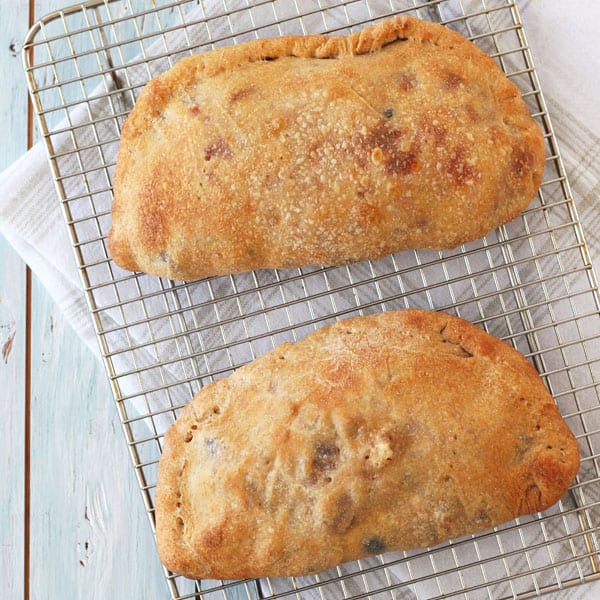 Golden baked toaster oven calzones cooling a rack.