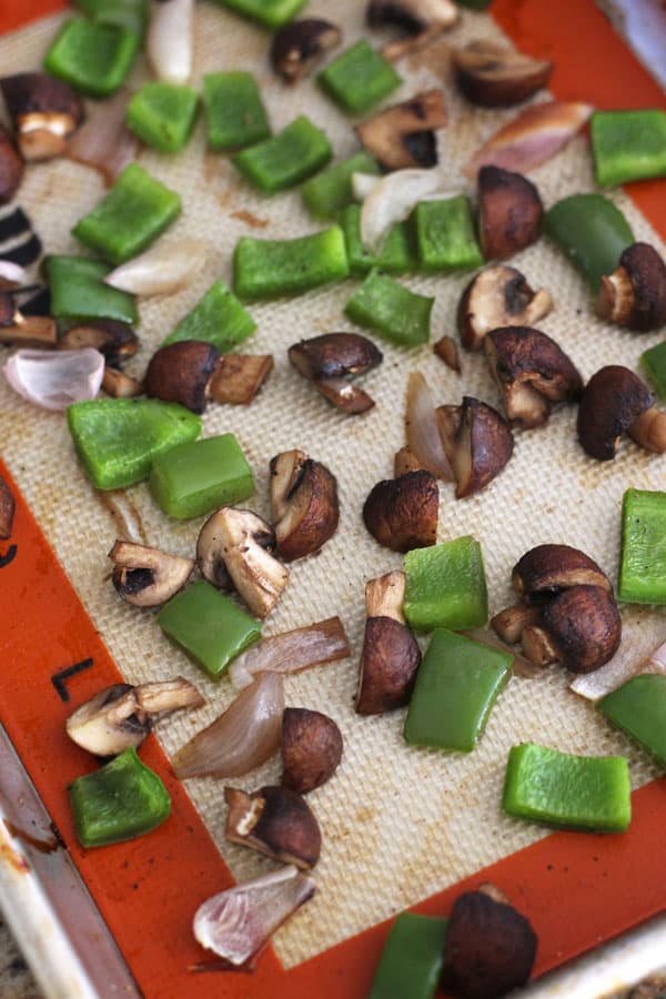 Roasted vegetables on a silcone baking mat lined sheet pan.