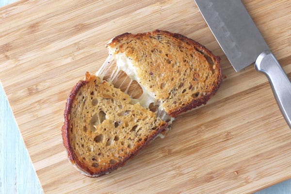 A grilled cheese sandwich sliced open on a cutting board