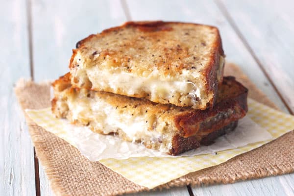 Gooey grilled cheese sandwich slices stacked on a piece of parchment.