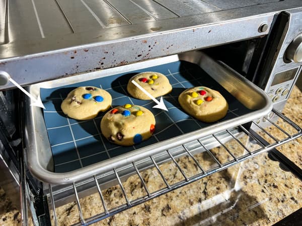 Arrows pointing to bunched areas on baking mat inside toaster oven.