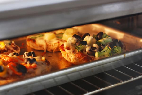 pizza bagels baking on a metal pan
