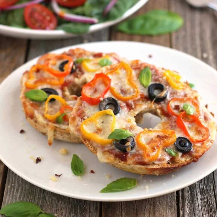 Plate of pizza bagels next to a bowl of salad.