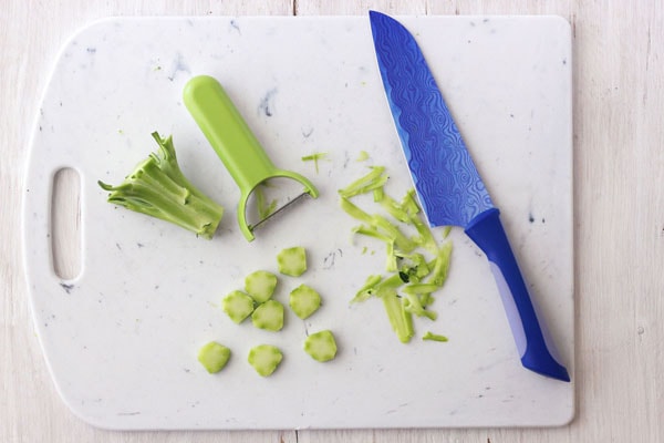 Broccoli stem peeled and sliced into coins on a cutting board.