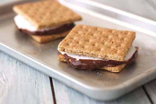 Two gooey s'mores on a baking pan.