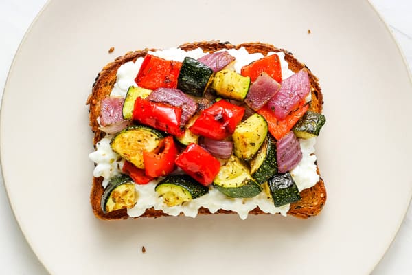 Colorful mix of roasted veggies on toast with cottage cheese.